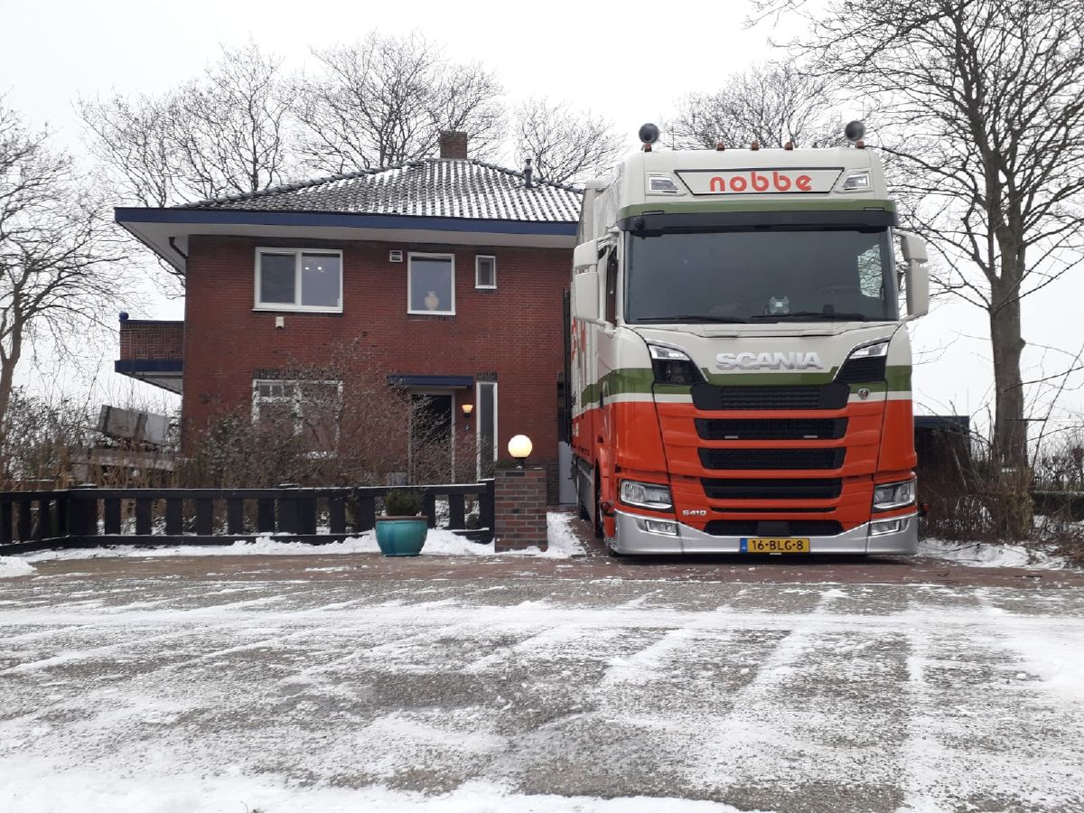 Een scania Verhuiswagen van Verhuisbedrijf Nobbe geparkeerd bij een vrijstaande woning.