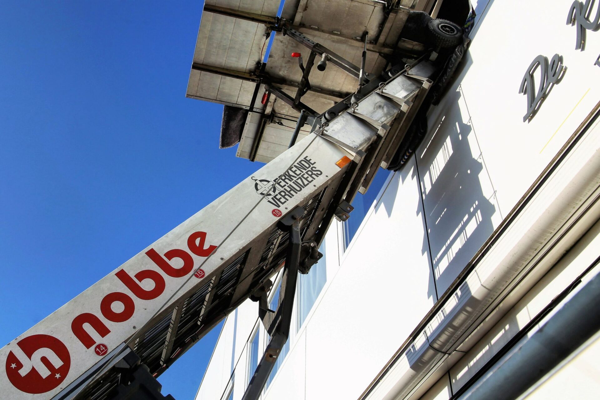 Een detail van de verhuislift van Verhuisbedrijf Nobbe met daarop het logo, de bedrijfsnaam en het logo van de brancheorganisatie Erkende Verhuizers.