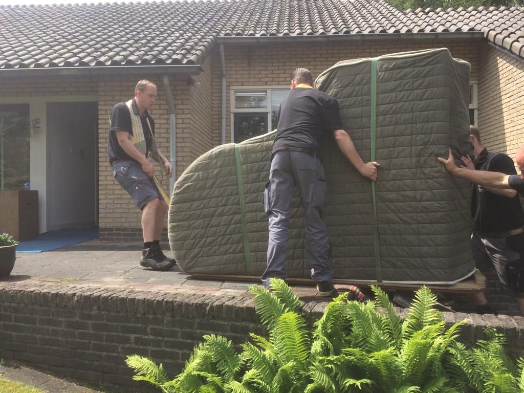 De verhuizers van Verhuisbedrijf Nobbe werken met elkaar een vleugel een trap op,